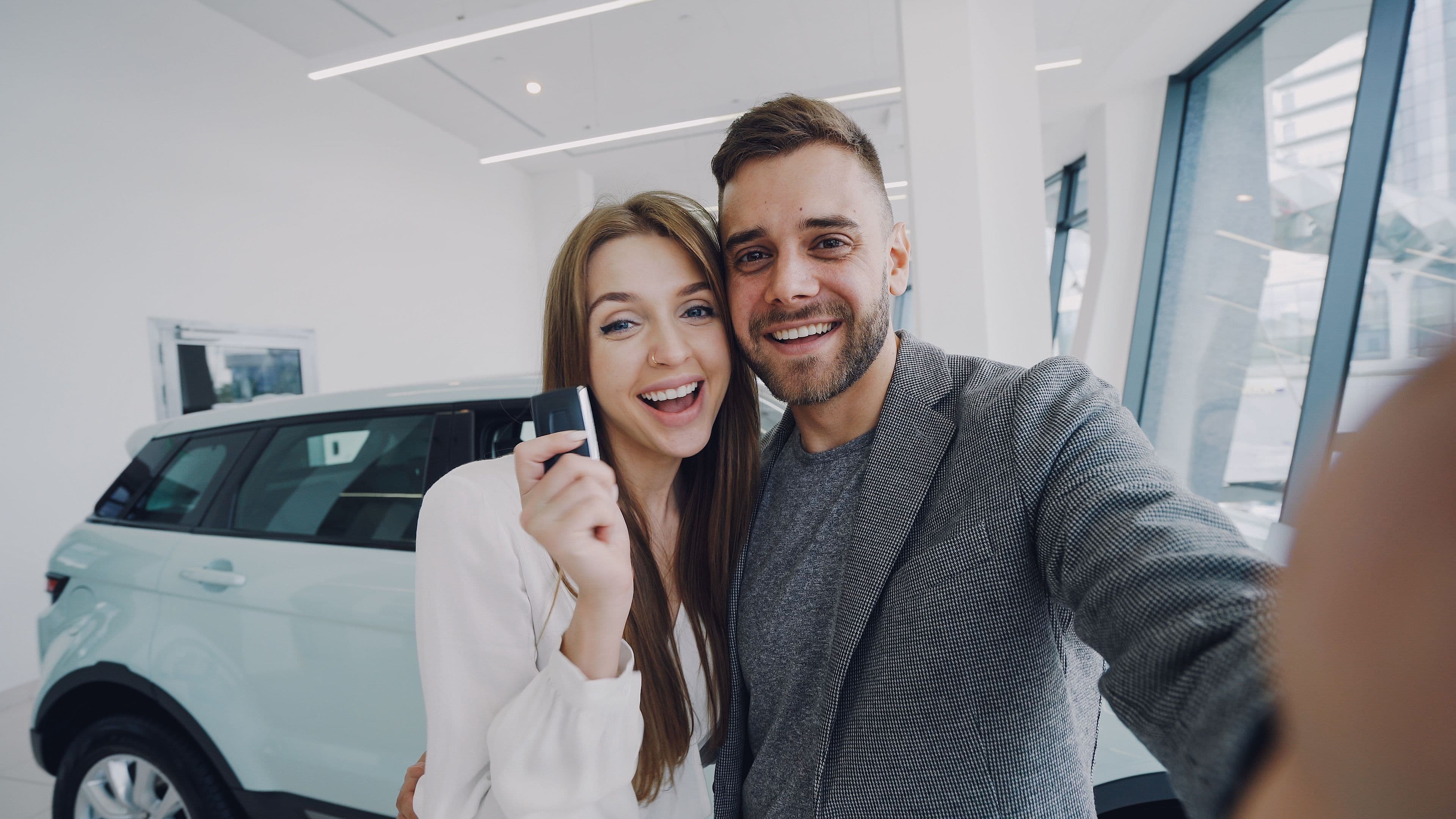 A couple smiling and holding the key to their new car